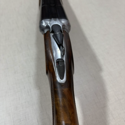 Espingarda de canos duplos com madeira polida e detalhes metálicos gravados