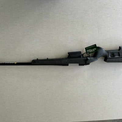 Espingarda preta com etiqueta verde sobre superfície clara