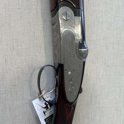 Espingarda de caça em madeira escura e metal com gravações e etiqueta da marca SPORTAROLA