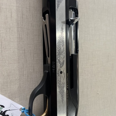 Espingarda com acabamento em metal e madeira, texto gravado e etiqueta branca pendurada