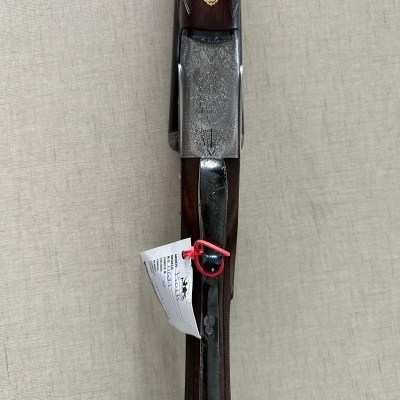 Espingarda de madeira castanha e metal prateado com etiqueta pendurada.