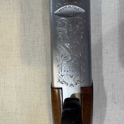 Parte metálica e madeira de uma arma com gravações e texto