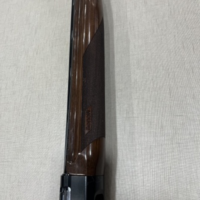 Espingarda com coronha de madeira castanha e empunhadura texturizada em superfície bege