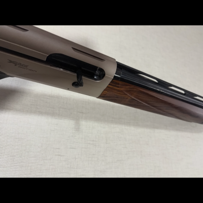 Espingarda com coronha de madeira castanha e corpo metálico cinza com inscrição Xplor action