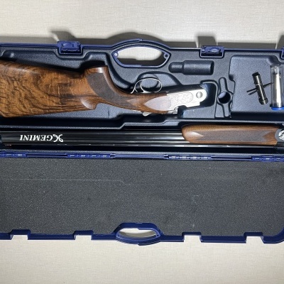 Estojo aberto com espingarda desmontada em madeira e metal dentro.