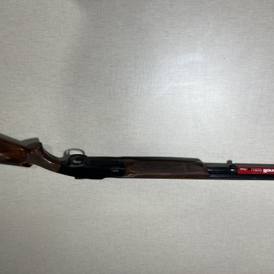 Espingarda cano duplo com madeira castanha e canos pretos com rótulo besnaga rugo