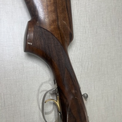 Coronha de madeira escura com gatilho dourado e detalhes metálicos prateados