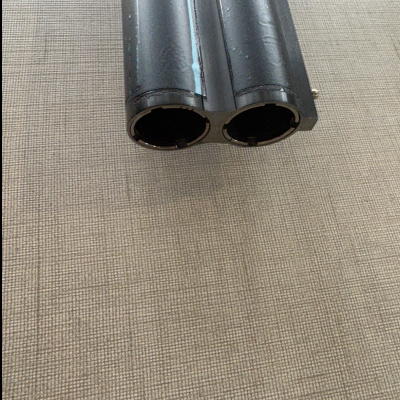 Ponta de duas barras cilíndricas pretas em superfície bege texturizada.