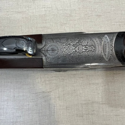 Detalhe de arma de fogo com gravações florais e madeira escura