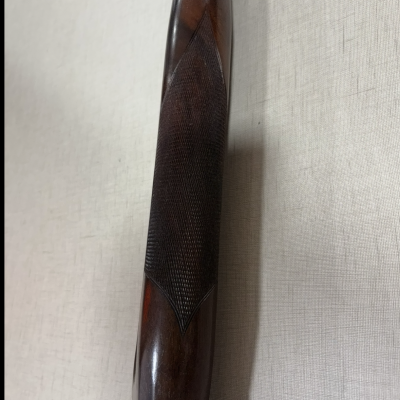 Parte superior de arma de fogo em madeira escura com textura quadriculada