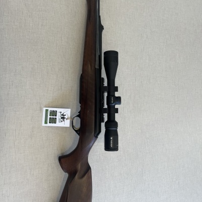Espingarda com coronha em madeira castanha e cano preto, com luneta e etiqueta pendurada