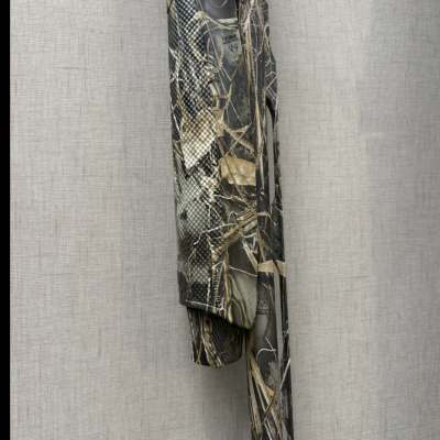 Peça de roupa camuflada pendurada com padrão de folhas e ramos secos