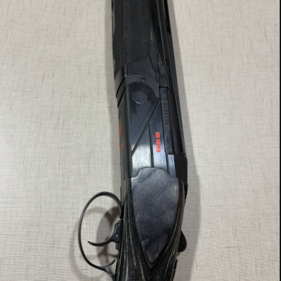 Espingarda negra Beretta com empunhadura em madeira escura sobre tecido bege