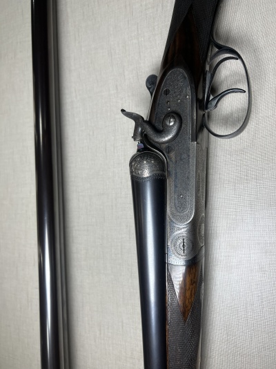 Espingarda de canos duplos em metal e madeira escura com detalhes gravados