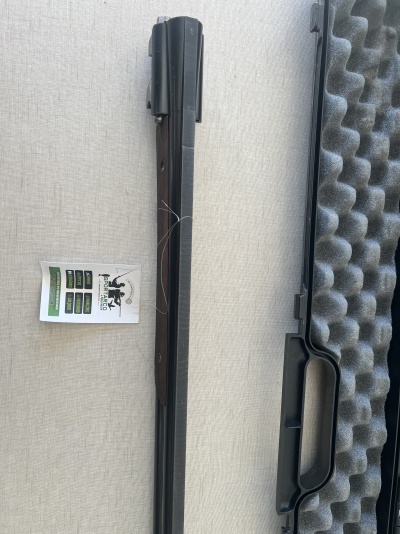 Cano de arma de fogo preta com etiqueta ao lado e estojo acolchoado cinzento