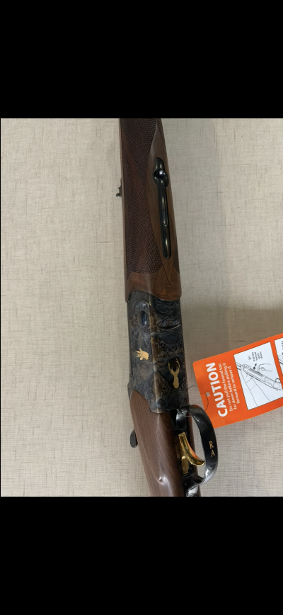 Espingarda de caça com acabamento em madeira e metal com gravações e detalhe dourado