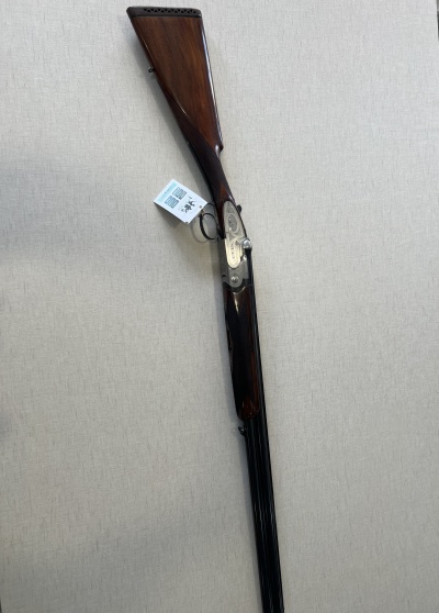 Espingarda de madeira e metal com etiqueta pendurada sobre fundo bege