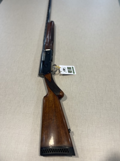 Rifle com coronha de madeira e armação preta sobre fundo beige