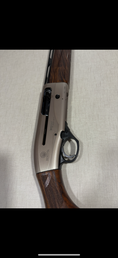 Espingarda Beretta com corpo metálico e detalhes em madeira sobre superfície clara