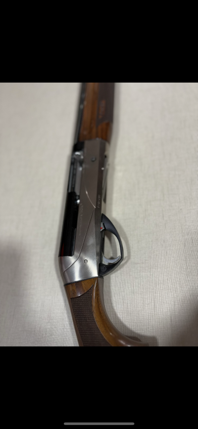 Espingarda com madeira castanha e partes metálicas prateadas e pretas