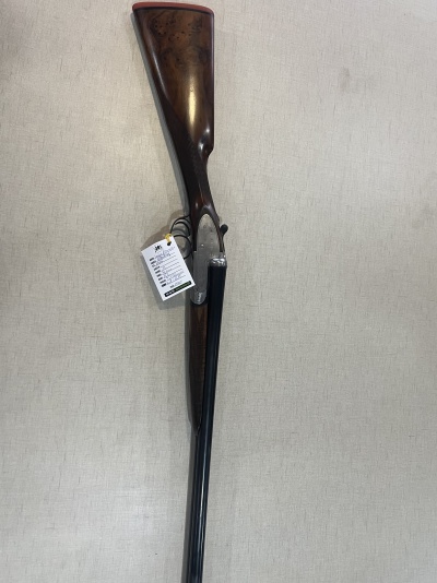 Espingarda com coronha de madeira castanha e canos pretos pendurada na parede