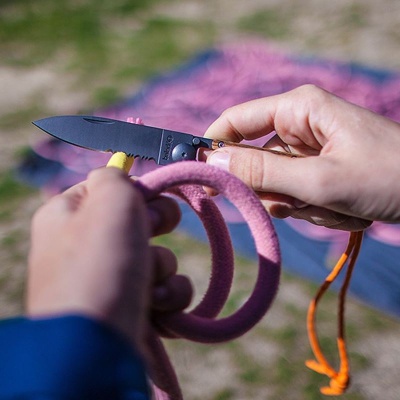 Pessoa cortando corda rosa com faca dobrável preta