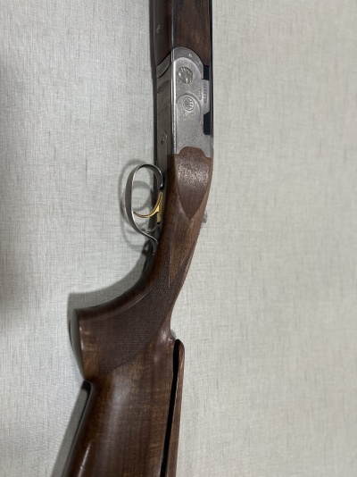 Espingarda com coronha de madeira escura e partes metálicas prateadas