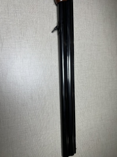 Parte do cano de uma espingarda de canos paralelos em metal preto sobre superfície cinzenta