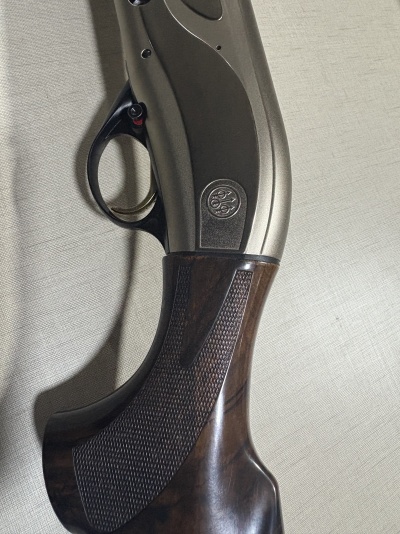 Pega de espingarda em madeira castanha com corpo metálico cinzento e gatilho preto