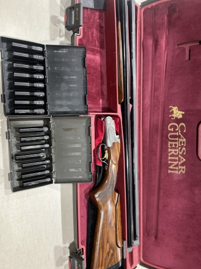 Espingarda desmontada em estojo vermelho com cartuchos em estojos pretos