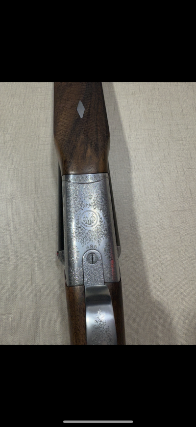 Espingarda com coronha de madeira e gravações metálicas detalhadas.