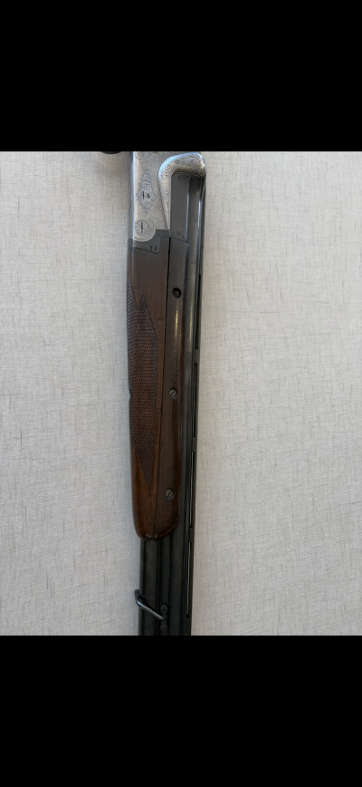 Espingarda com madeira escura texturizada e metal prateado gravado