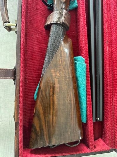 Estojo vermelho com arma de cano duplo e coronha de madeira escura