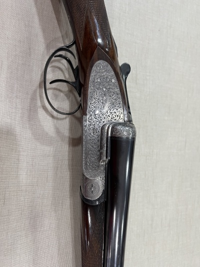 Espingarda de canos duplos com gravações ornamentais na parte metálica e madeira escura trabalhada