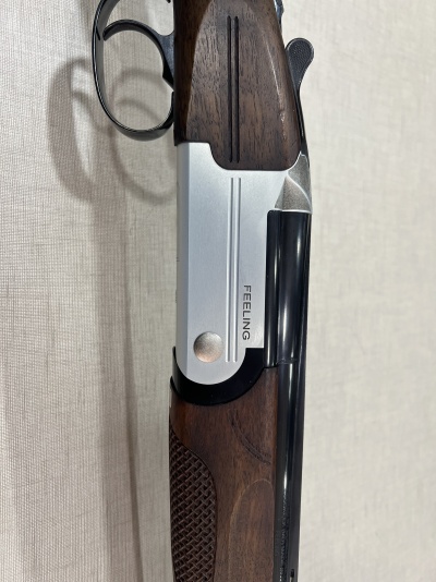 Espingarda com madeira escura e metal prateado com a palavra FEELING