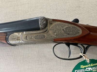 Espingarda de canos sobrepostos com detalhes gravados em metal prateado e madeira castanha