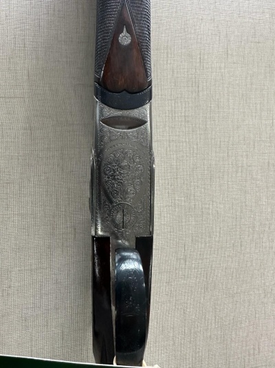 Parte inferior de espingarda com madeira castanha e metal prateado com gravações