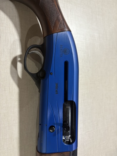 Espingarda azul Beretta com punho em madeira castanha e gatilho prateado