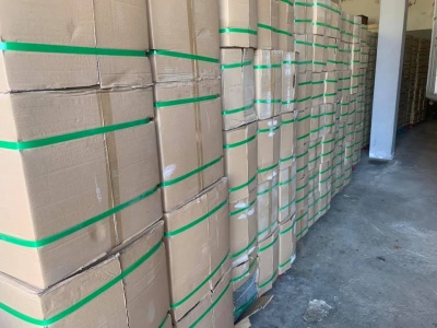 Caixas de cartão empilhadas com cintas verdes num armazém