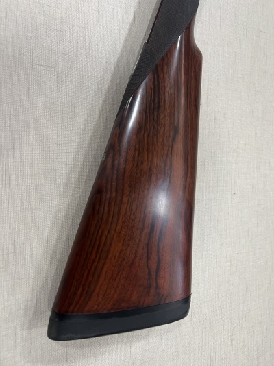 Cabo de arma em madeira castanha com base preta sobre fundo claro