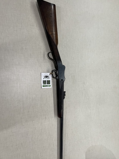 Espingarda com coronha de madeira e cano metálico pendurada em parede