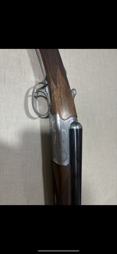 Espingarda de canos duplos com coronha em madeira escura e partes metálicas gravadas