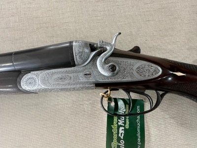 Espingarda de cano duplo com detalhes metálicos gravados e punho de madeira escura