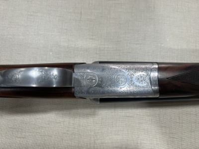 Espingarda com madeira castanha e metal gravado sobre tecido bege