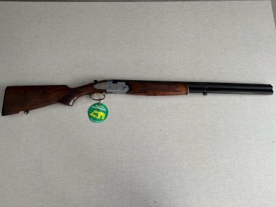 Espingarda de canos paralelos com madeira castanha e canos pretos sobre superfície cinzenta