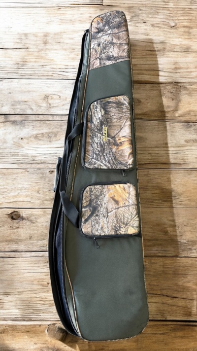 Bolsa de transporte verde com detalhes camuflados e bolsos sobre chão de madeira