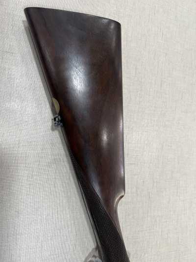 Cola de espingarda de madeira escura polida sobre tecido bege