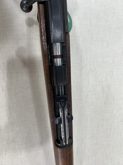 Rifle com coronha em madeira e partes metálicas pretas com visor ajustável