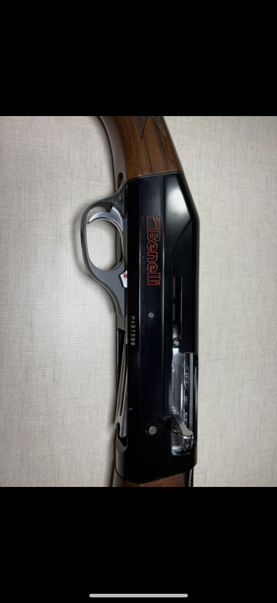 Espingarda Benelli com coronha de madeira e corpo metálico preto