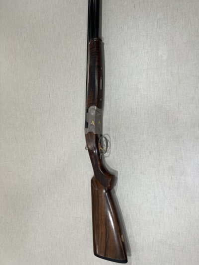 Espingarda de canos duplos com madeira castanha e metal cinza com detalhes dourados